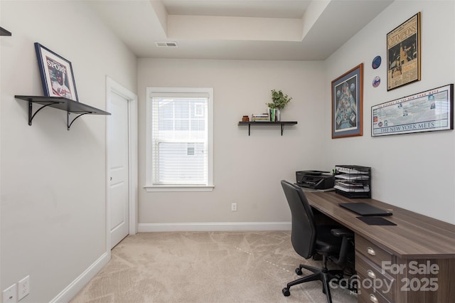 carpeted office space with baseboards, visible vents, and a tray ceiling