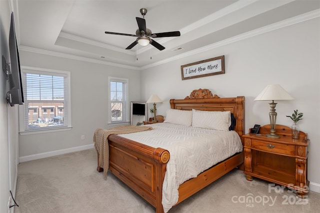 bedroom with baseboards, light colored carpet, ceiling fan, ornamental molding, and a tray ceiling