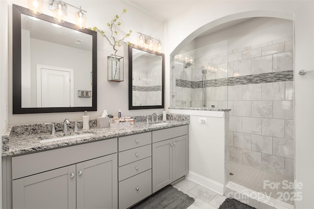 bathroom featuring double vanity, walk in shower, a sink, and tile patterned floors