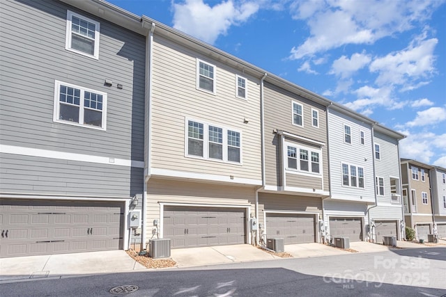 exterior space with an attached garage, cooling unit, and a residential view