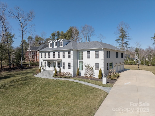 colonial-style house with concrete driveway, an attached garage, and a front lawn