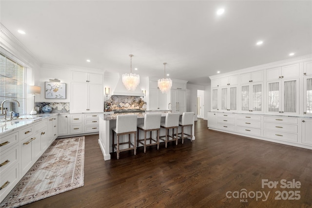 kitchen featuring a kitchen island with sink, a sink, white cabinetry, and a kitchen breakfast bar