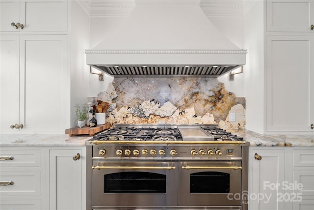 kitchen featuring range with two ovens, white cabinets, and premium range hood