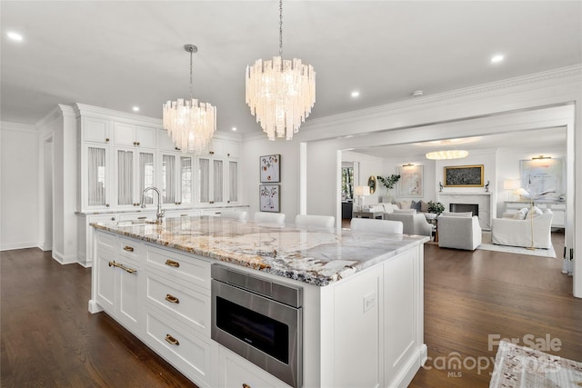 kitchen with stainless steel microwave, a fireplace, a sink, and white cabinetry