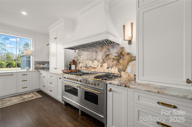 kitchen with dark wood finished floors, ornamental molding, white cabinetry, double oven range, and premium range hood