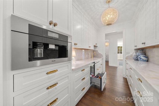 kitchen featuring a sink, white cabinetry, backsplash, dark wood finished floors, and crown molding