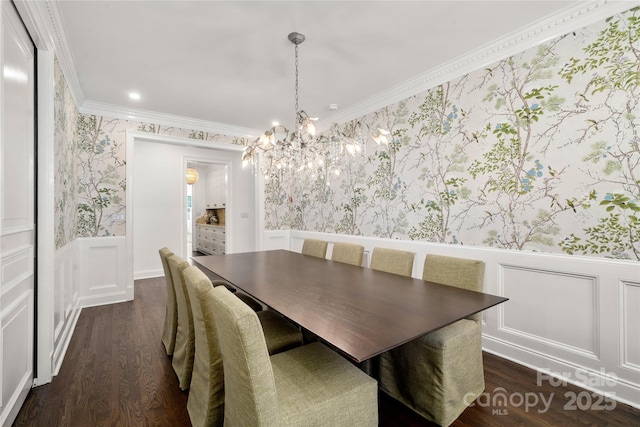 dining space with wallpapered walls, ornamental molding, dark wood finished floors, and wainscoting