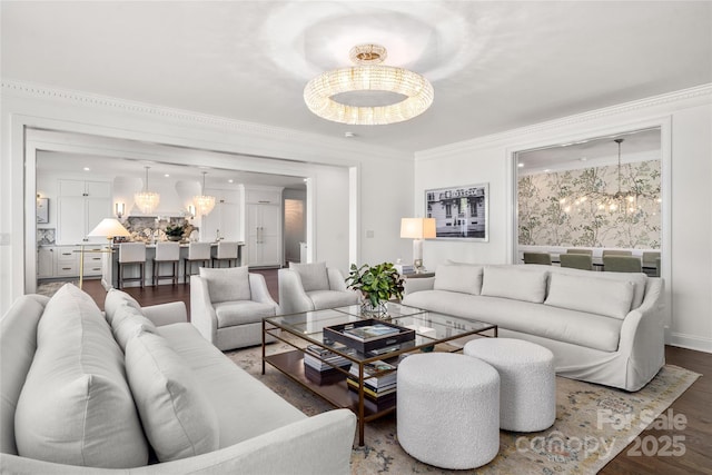 living room with baseboards, crown molding, a chandelier, and wood finished floors