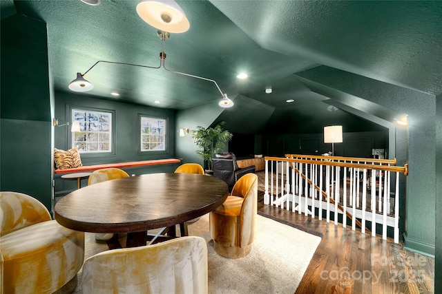 recreation room featuring a textured ceiling, vaulted ceiling, and wood finished floors