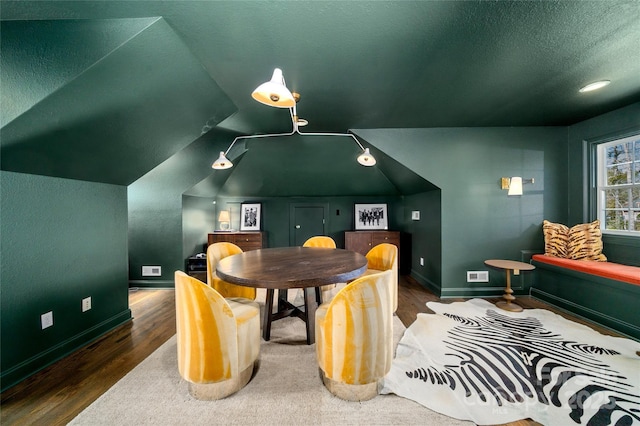 dining room with baseboards, visible vents, wood finished floors, vaulted ceiling, and a textured ceiling