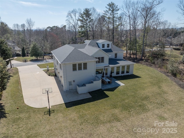 exterior space with a patio area, roof with shingles, and a yard