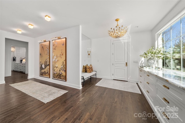 foyer featuring baseboards, dark wood-type flooring, and a notable chandelier