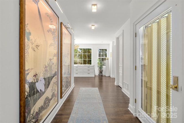 hallway featuring baseboards and dark wood-type flooring