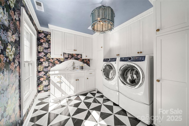 washroom featuring light floors, washing machine and clothes dryer, cabinet space, an inviting chandelier, and wallpapered walls