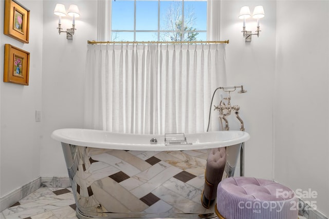 full bathroom with a freestanding bath, marble finish floor, and baseboards