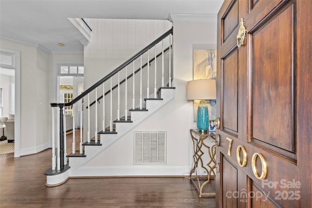 staircase with visible vents, baseboards, wood finished floors, and crown molding