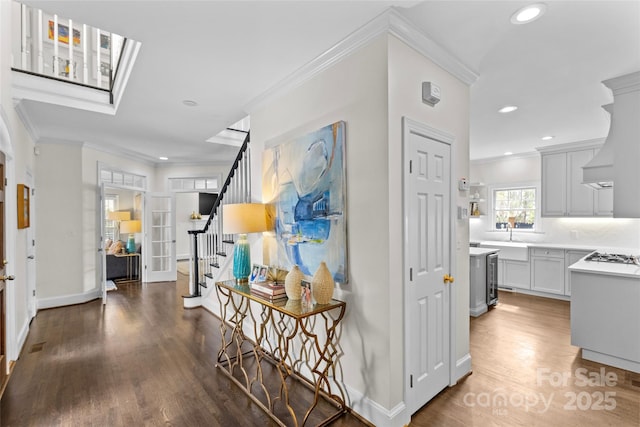 corridor with stairway, ornamental molding, recessed lighting, a skylight, and wood finished floors