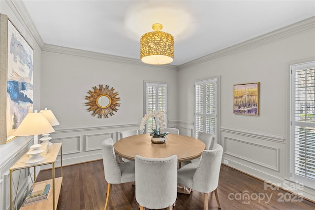 dining area featuring dark wood-type flooring, a decorative wall, crown molding, and wainscoting