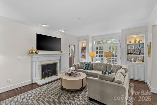 living room featuring a healthy amount of sunlight, dark wood finished floors, and crown molding