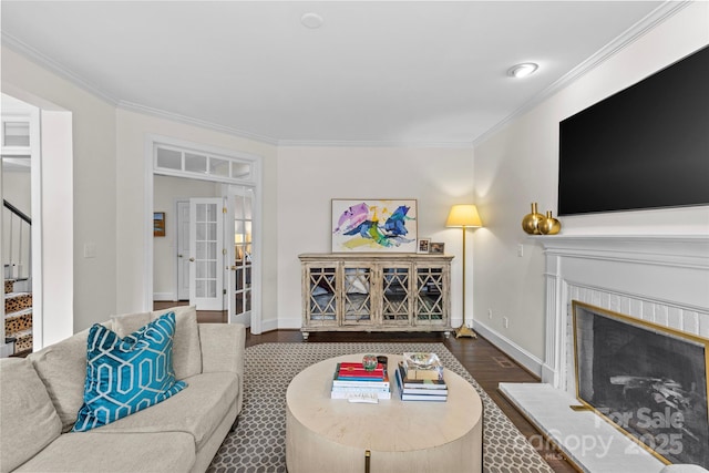 living area with stairway, baseboards, a fireplace, dark wood-style flooring, and ornamental molding