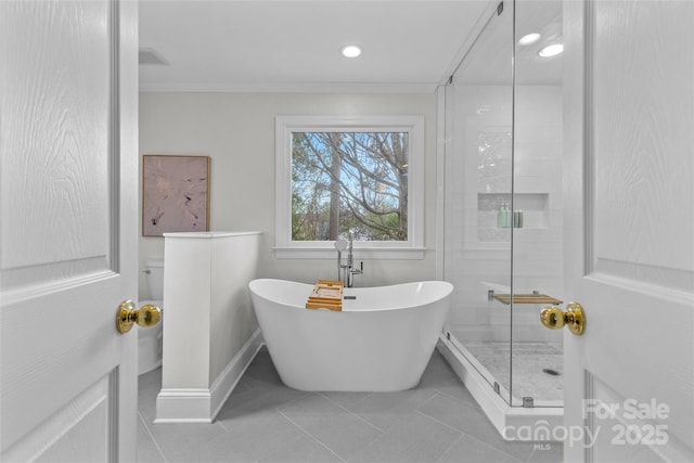 full bath featuring a freestanding tub, a stall shower, crown molding, tile patterned flooring, and baseboards