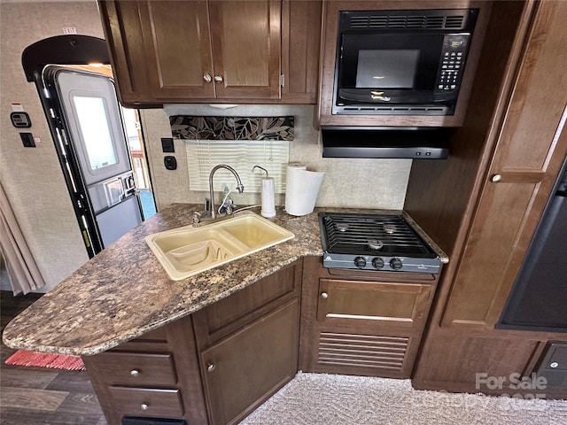 kitchen featuring gas stovetop, backsplash, a sink, dark stone countertops, and black microwave