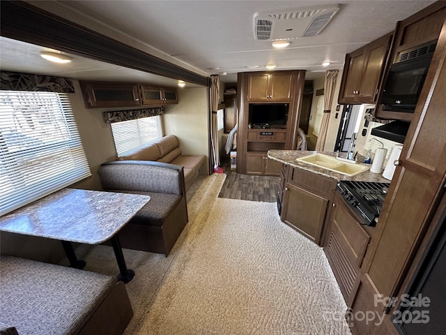 interior space featuring black microwave, visible vents, a sink, and open floor plan