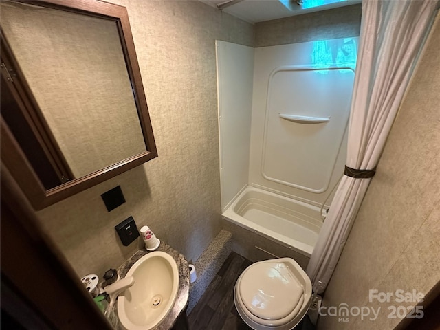 full bath with toilet, shower / bathtub combination with curtain, and a sink