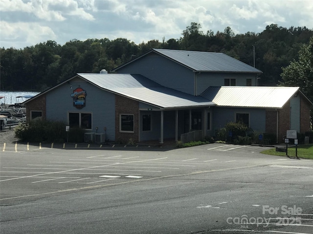 view of building exterior featuring uncovered parking, cooling unit, and a wooded view