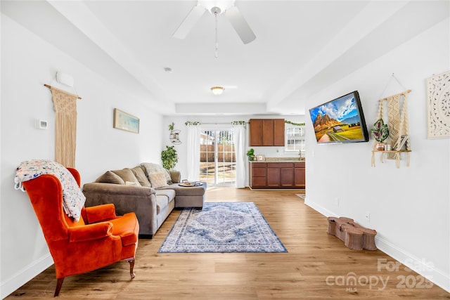 living room with baseboards, a ceiling fan, and light wood-style floors