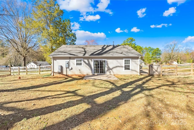 rear view of property featuring a yard, a patio area, fence, and a gate