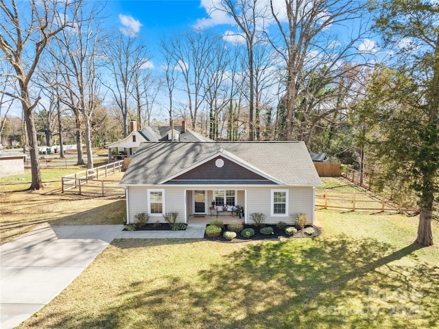 view of front of house with a shingled roof, fence, a porch, and a front yard