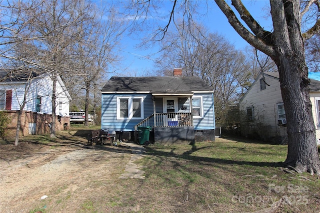 view of front of property with covered porch, a shingled roof, crawl space, a chimney, and a front yard