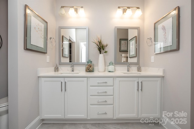 bathroom with a sink, toilet, and double vanity