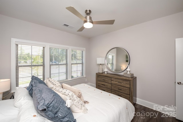 bedroom featuring multiple windows, wood finished floors, visible vents, and baseboards