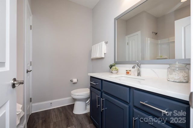 full bath with toilet, wood finished floors, vanity, baseboards, and walk in shower