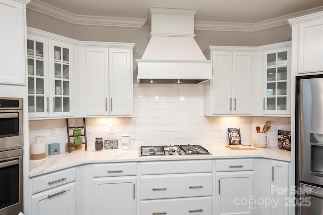 kitchen featuring ornamental molding, appliances with stainless steel finishes, white cabinetry, and custom range hood