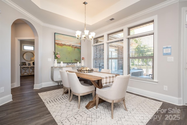 dining room with arched walkways, a raised ceiling, and dark wood finished floors