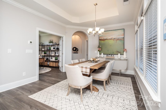 dining room featuring dark wood finished floors, arched walkways, a raised ceiling, and a notable chandelier