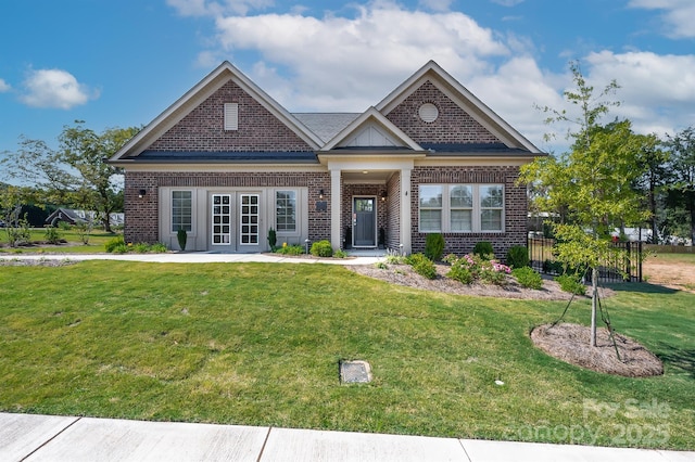 craftsman-style home with french doors, brick siding, a front lawn, and fence