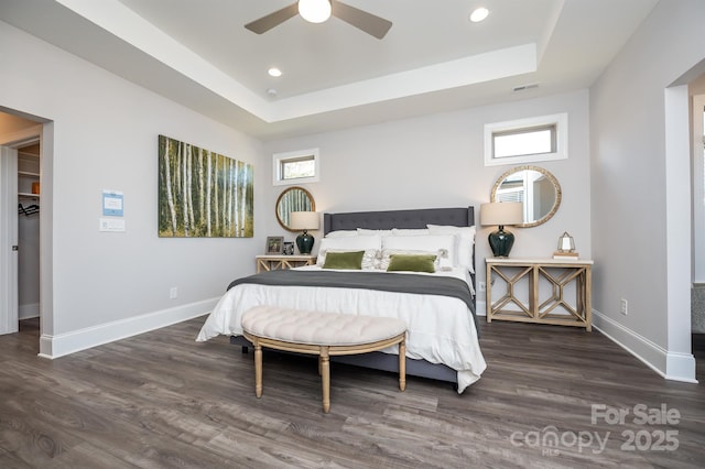 bedroom featuring baseboards, a raised ceiling, and wood finished floors