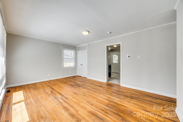 spare room with light wood-style floors, visible vents, crown molding, and baseboards