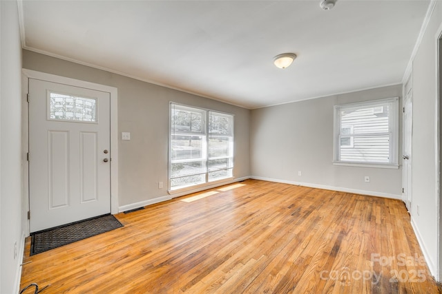 foyer entrance with ornamental molding, plenty of natural light, and light wood-style flooring