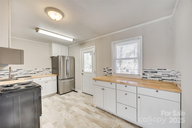 kitchen with wood counters, freestanding refrigerator, crown molding, black range with electric cooktop, and a sink