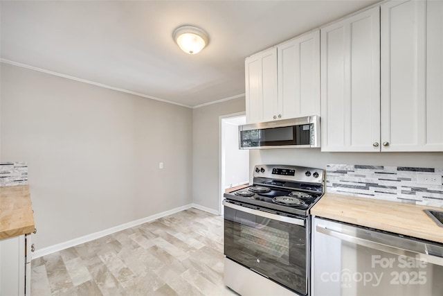 kitchen with baseboards, butcher block counters, stainless steel appliances, crown molding, and white cabinetry