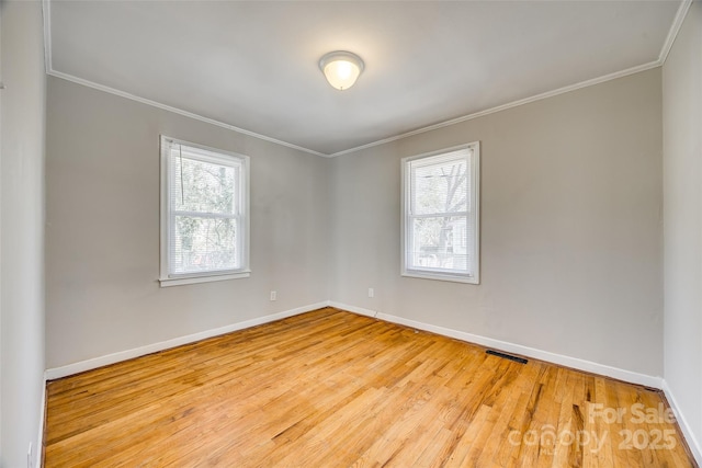 empty room with visible vents, ornamental molding, and a wealth of natural light