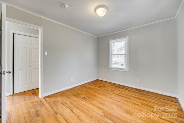 unfurnished room featuring light wood-type flooring, crown molding, and baseboards