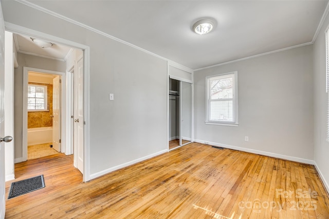 unfurnished bedroom featuring ornamental molding, visible vents, light wood finished floors, and multiple windows