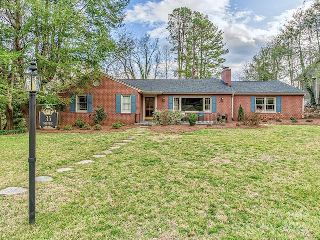 ranch-style house with brick siding, a shingled roof, a chimney, and a front yard