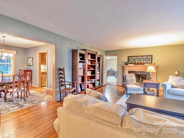 living area with an inviting chandelier, baseboards, wood finished floors, and a high end fireplace